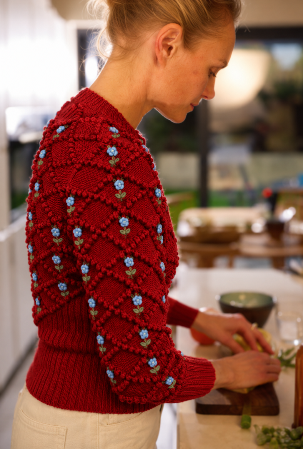 Side view of Karla handknitted baby merino wool cardigan in Grenade Red with Ice Blue and Sage Green embroidered roses