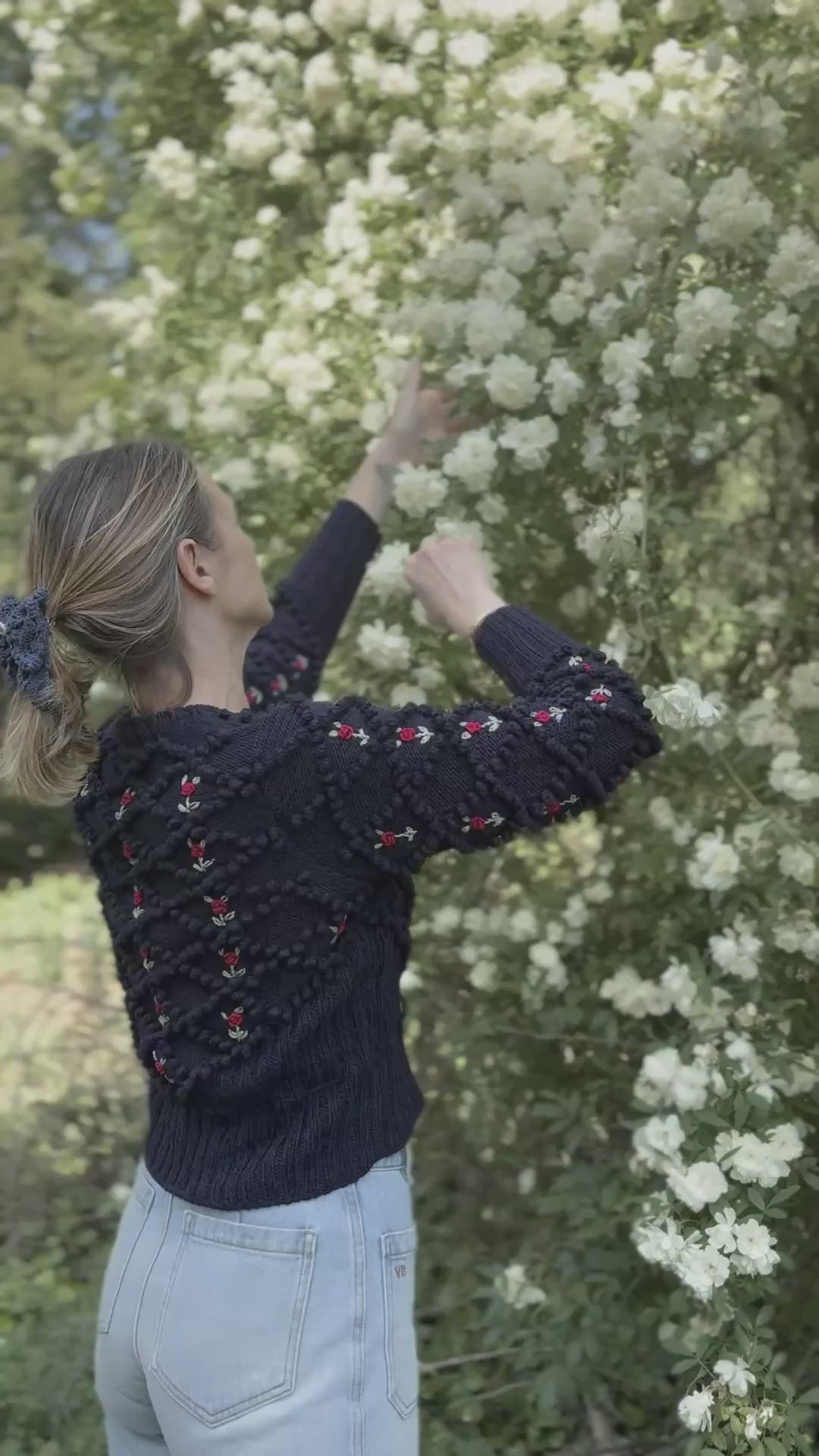 michaela buerger dark blue karla cardigan in mercerized cotton, worn by woman in a beautiful garden